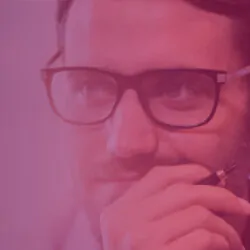Image in pink of a pensive man with beard and black frame glasses