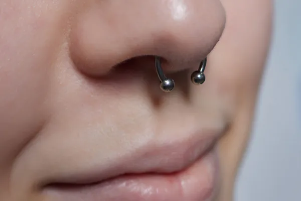 Closeup of a mouth and nose adorned with a septum piercing, one of the Nose Piercing Trends 2024 