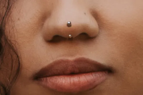A woman's lower face, her nose adorned with a rhino piercing