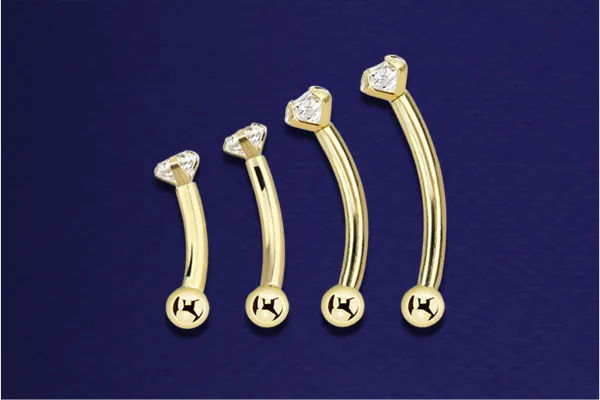Four gold curved barbells in different sizes with a prong set transparent crystal