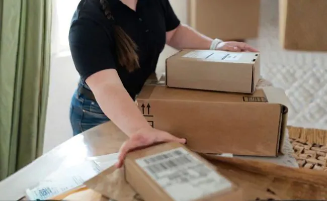 A woman wearing jeans and a black shirt is handling packages