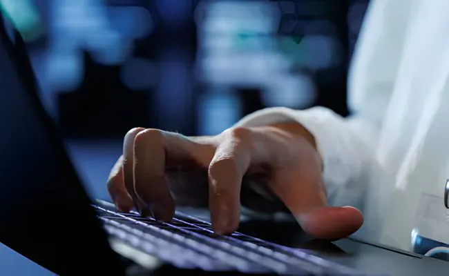 A hand is typing on a laptop keyboard