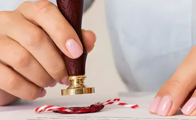 A document is marked with a seal using wax and a seal stamp