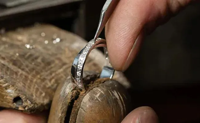 A ring is held in place with a ring clamp and worked on by a jeweller