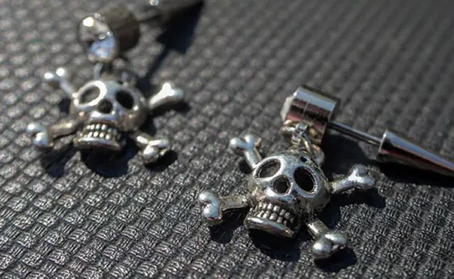 Two pieces of body jewellery with skull and bones design