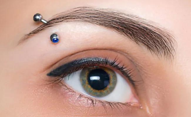 An eye and pierced eyebrow adorned with a curved barbell