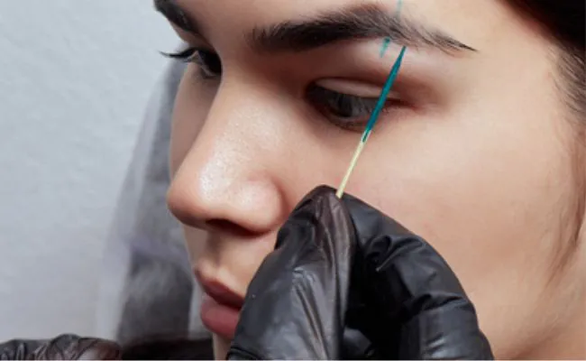 An eyebrow is marked with ink prior to getting pierced