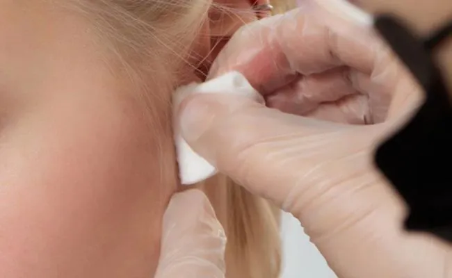 A daith piercing is being cleaned using a cotton round