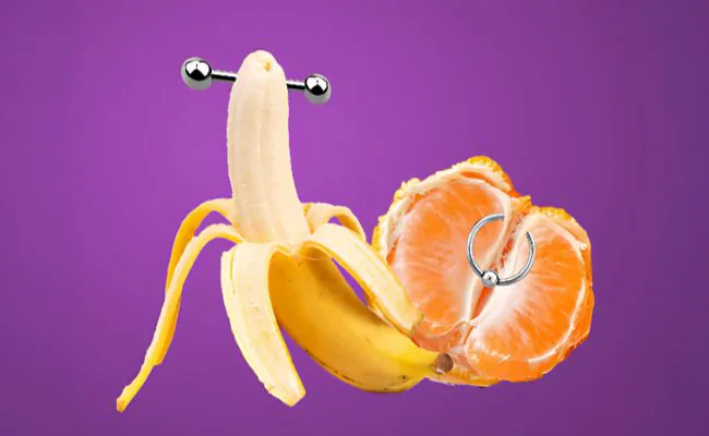 Two pieces of intimate jewellery, one going through the tip of a banana and one attached to an orange