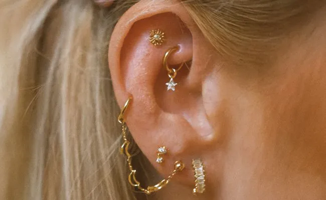Closeup of an ear adorned with different types of ear piercings including constellation piercings