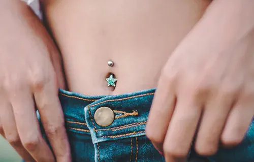 A pierced belly button, adorned with a curved barbell with a star shaped top